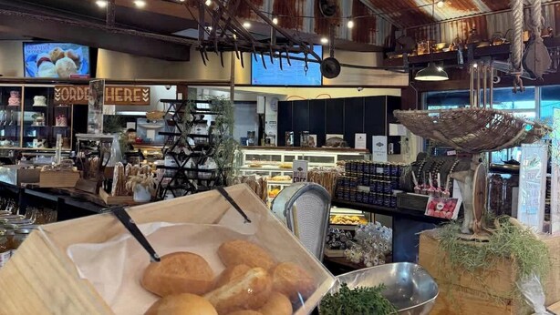 A rustic bakery interior with wooden display cases, hanging lights, and a visible counter area.