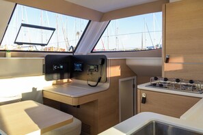 A compact galley with a stove, control panels, and a window overlooking the sea. - Sun-Kissed Sailing: A Luxurious Beach Experience in Valencia (Denia)