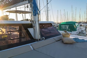 A marina with a sailboat docked, featuring a covered deck area with seating and a green canopy. - Sun-Kissed Sailing: A Luxurious Beach Experience in Valencia (Denia)