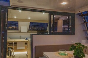 A modern bathroom with a large mirror, a sink, a plant, and a window with a view of the cityscape. - Sun-Kissed Sailing: A Luxurious Beach Experience in Valencia (Denia)