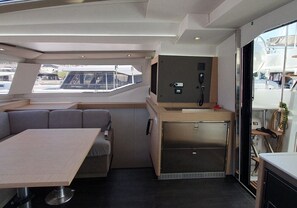 A compact interior with a dining area, a kitchenette, and a seating area. - Sun-kissed Sailing Adventure in Split-Dalmatia, Croatia (Seget Donji)