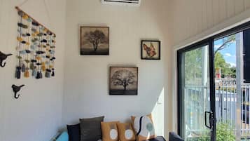 A cozy room with a bed, a hanging wall decoration, and a large window.