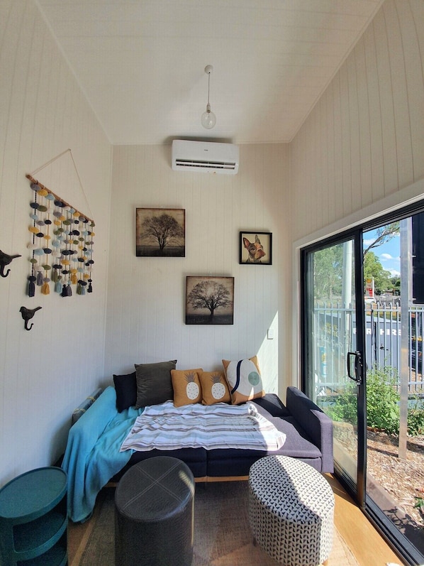 A cozy room with a bed, a hanging wall decoration, and a large window.