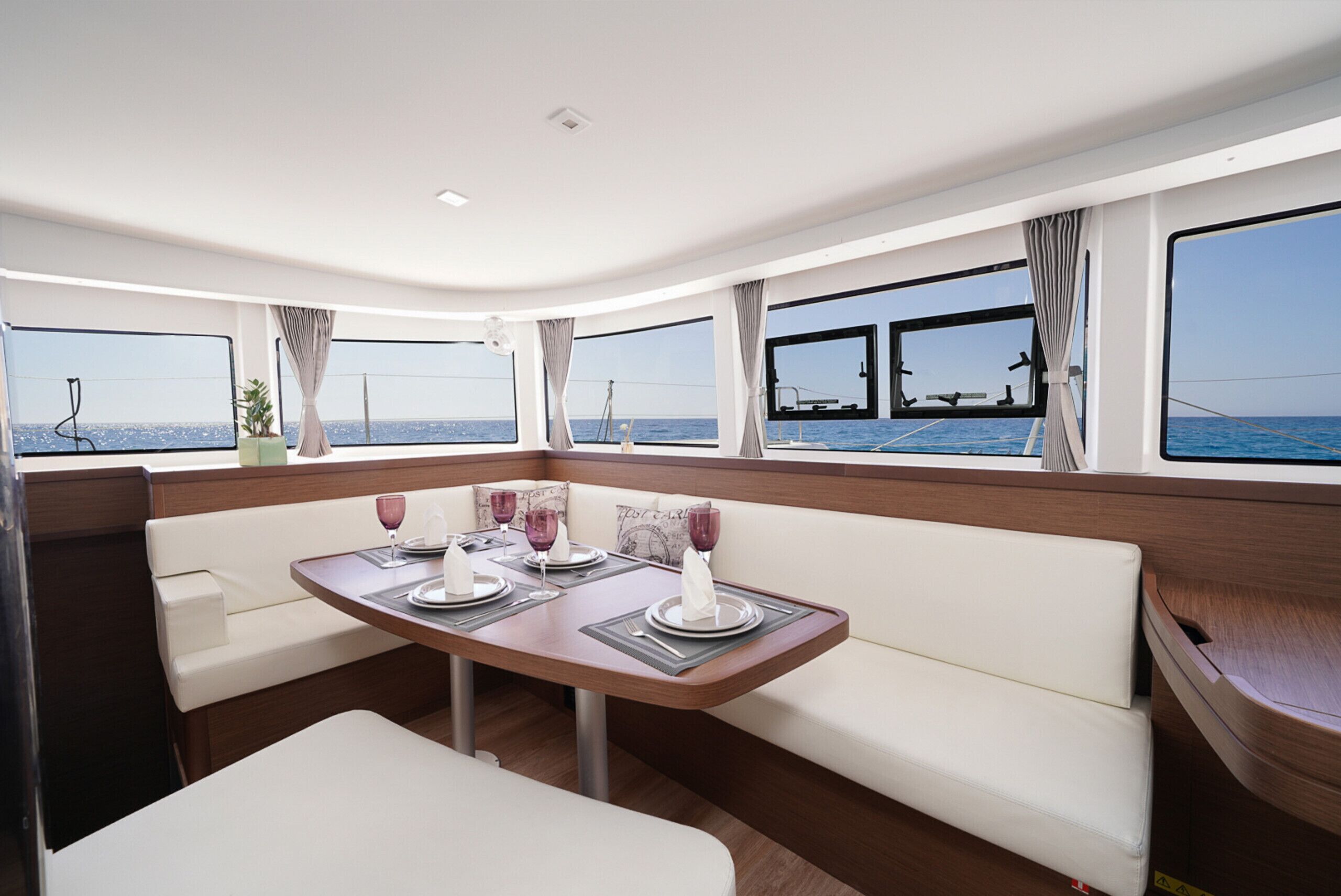 A dining area with a table set for two, large windows, and a view of the sea.