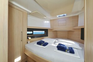 Ein kompakter, moderner Raum mit Etagenbett, Holzschrank, Flachbildfernseher und kleinem Tisch mit Lampe.