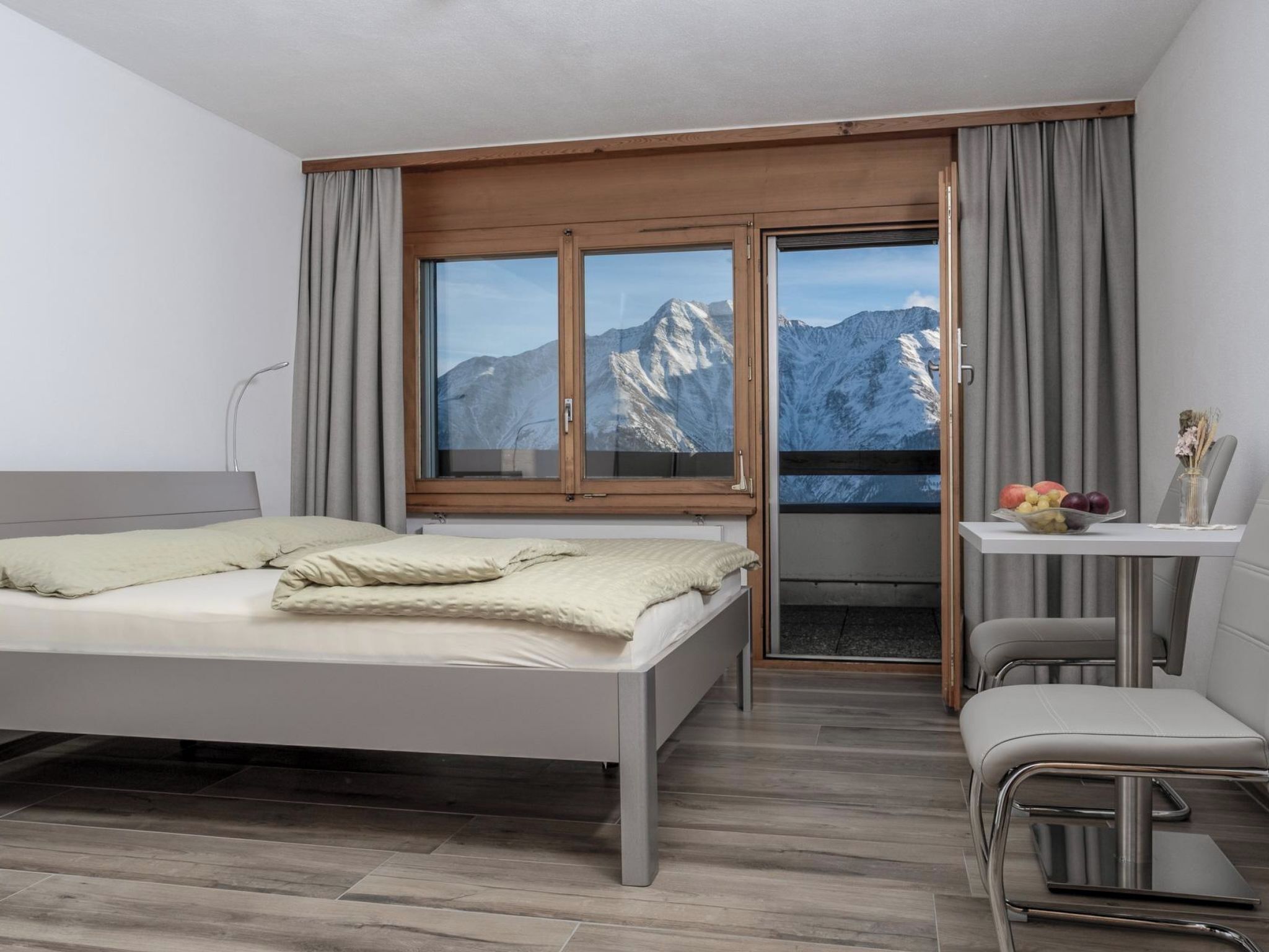 A modern hotel room with a bed, a desk, and a chair.