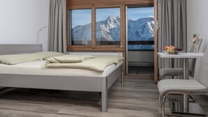 A modern hotel room with a bed, a desk, and a chair.