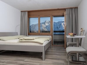 A modern hotel room with a bed, a desk, and a chair.