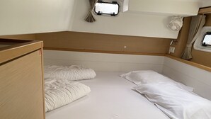 A small, single-bed room with a wooden headboard, a window with curtains, and a small shelf with a lamp. - Sun-Kissed Sailing Adventure in Istria, Croatia (Pula)