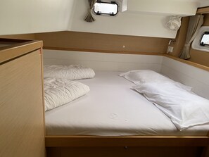A small, single-bed room with a wooden headboard, a window with curtains, and a small shelf with a lamp. - Sun-Kissed Sailing Adventure in Istria, Croatia (Pula)