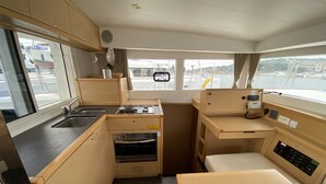 A compact galley kitchen with a sink, stove, oven, and a small dining area. - Sun-Kissed Sailing Adventure in Istria, Croatia (Pula)