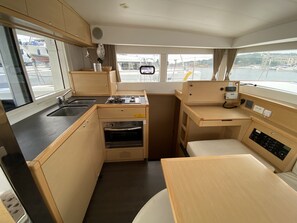 A compact galley kitchen with a sink, stove, oven, and a small dining area. - Sun-Kissed Sailing Adventure in Istria, Croatia (Pula)
