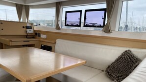 A compact interior with a wooden table, a cushioned bench, and a sofa with a textured pillow. - Sun-Kissed Sailing Adventure in Istria, Croatia (Pula)