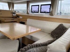 A compact interior with a wooden table, a cushioned bench, and a sofa with a textured pillow. - Sun-Kissed Sailing Adventure in Istria, Croatia (Pula)