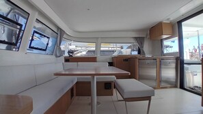 A compact galley with a central table, bench seating, and a small refrigerator. - Sun-Kissed Sailing Adventure in the Dodecanese Islands (Rodos)