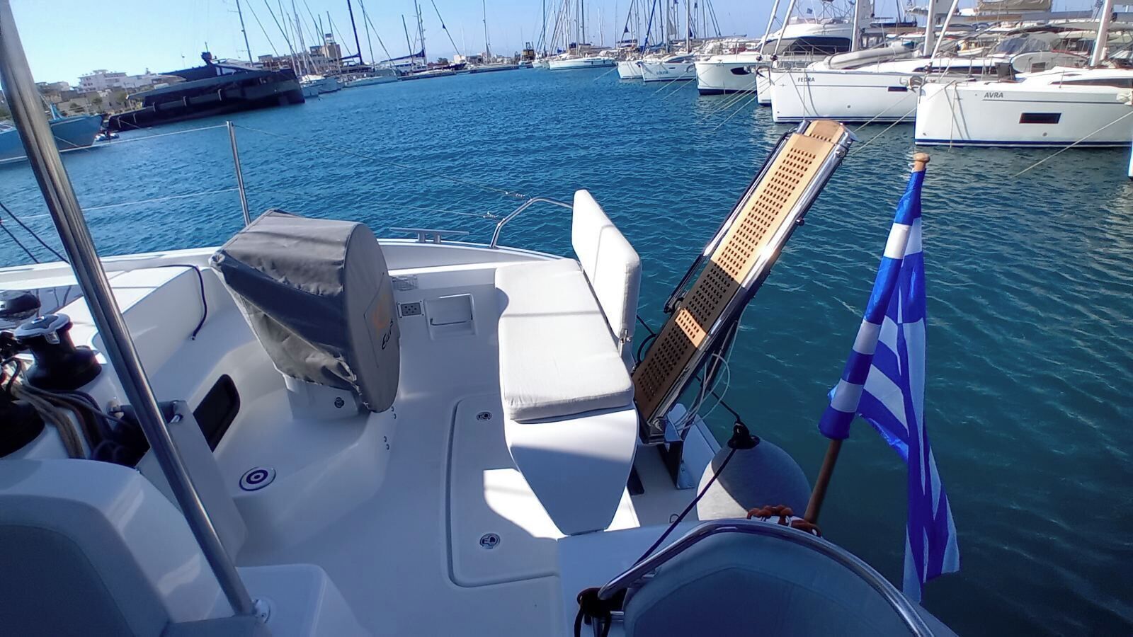 Un port de plaisance avec des bateaux amarrés, un drapeau et l’intérieur d’un bateau, comprenant un espace salon et un panneau de commande.