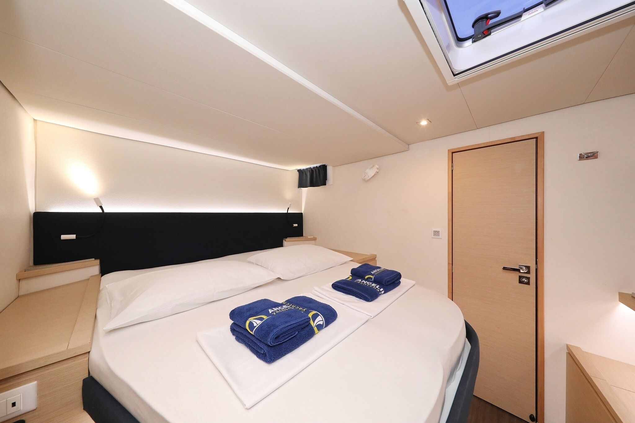 A hotel room with a bed, a TV, a door, and a bedside table.