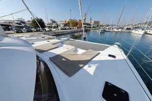 Een jachthaven met afgemeerde boten, een heldere lucht en een gebouw op de achtergrond.