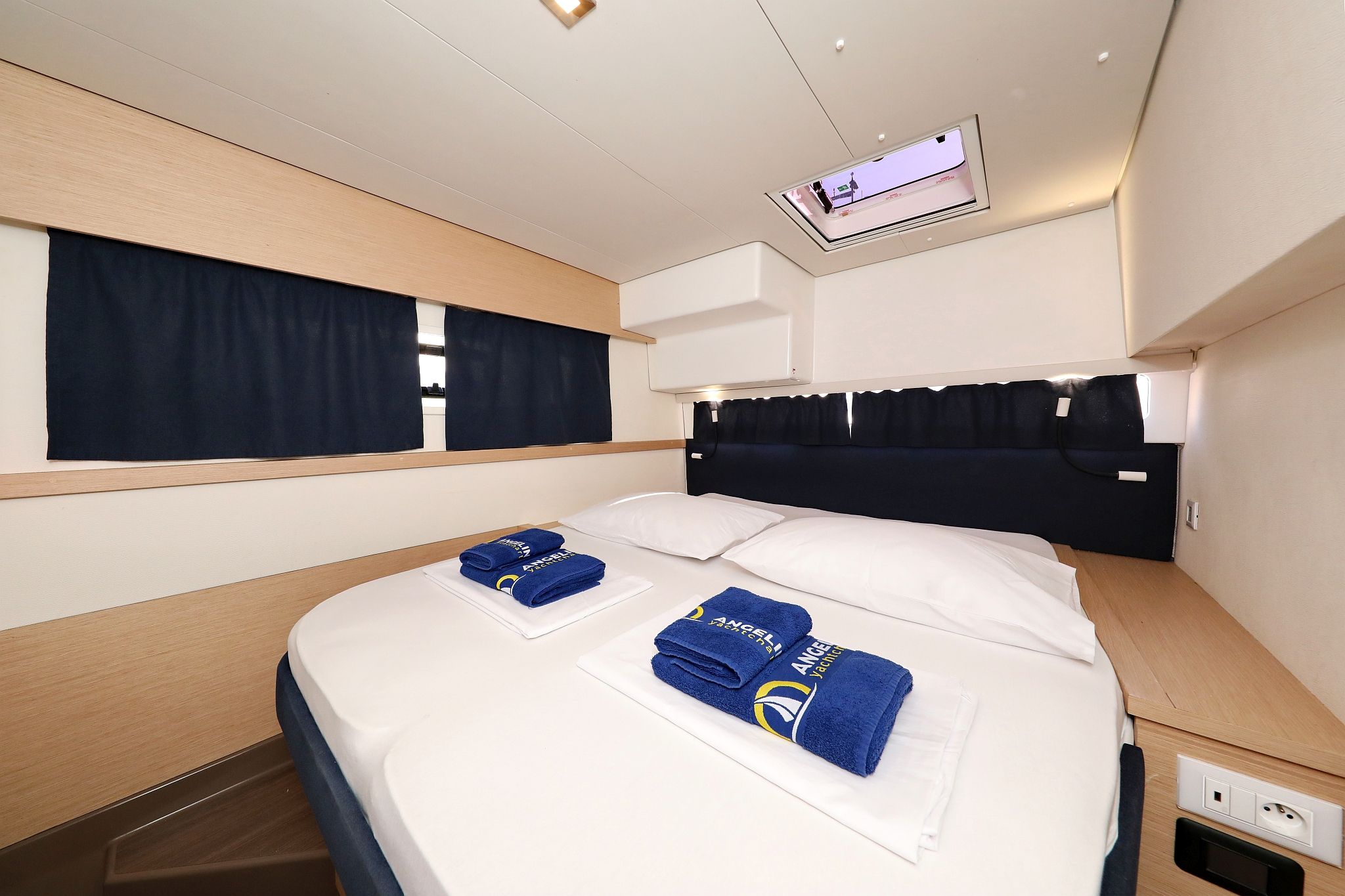Een hotelkamer met een bed, twee handdoeken, een televisie en een raam met gordijnen.
