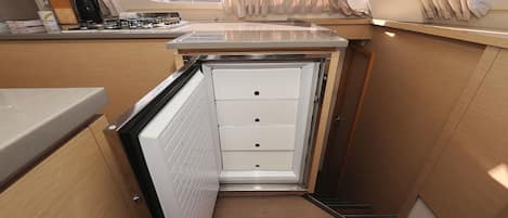 A compact kitchenette with a stove, a small countertop, and a window with curtains.