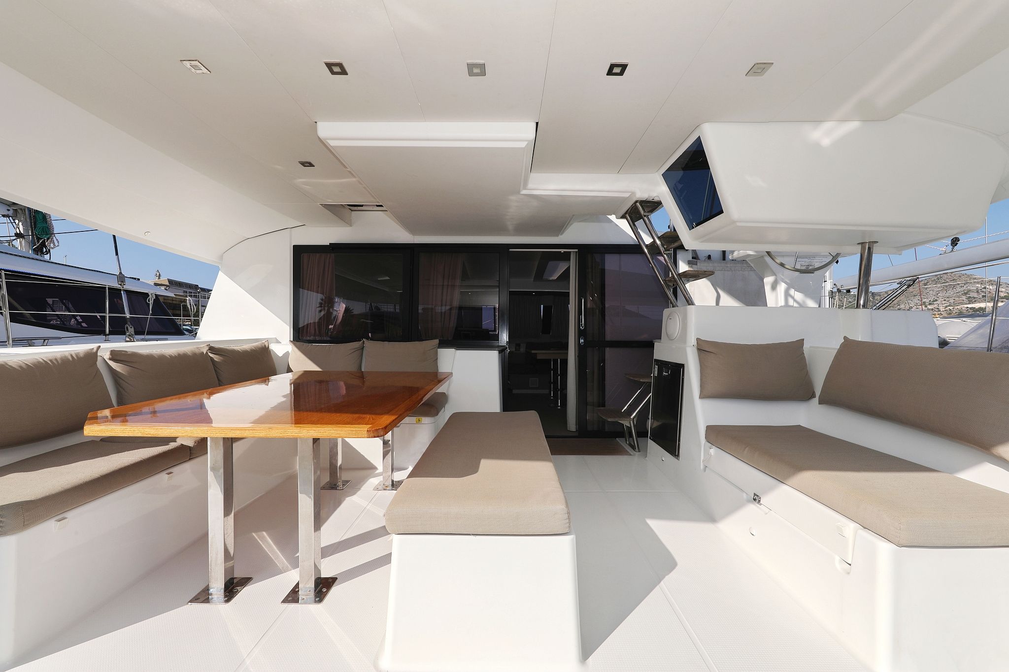 A yacht's interior with a dining area, seating, and a TV.
