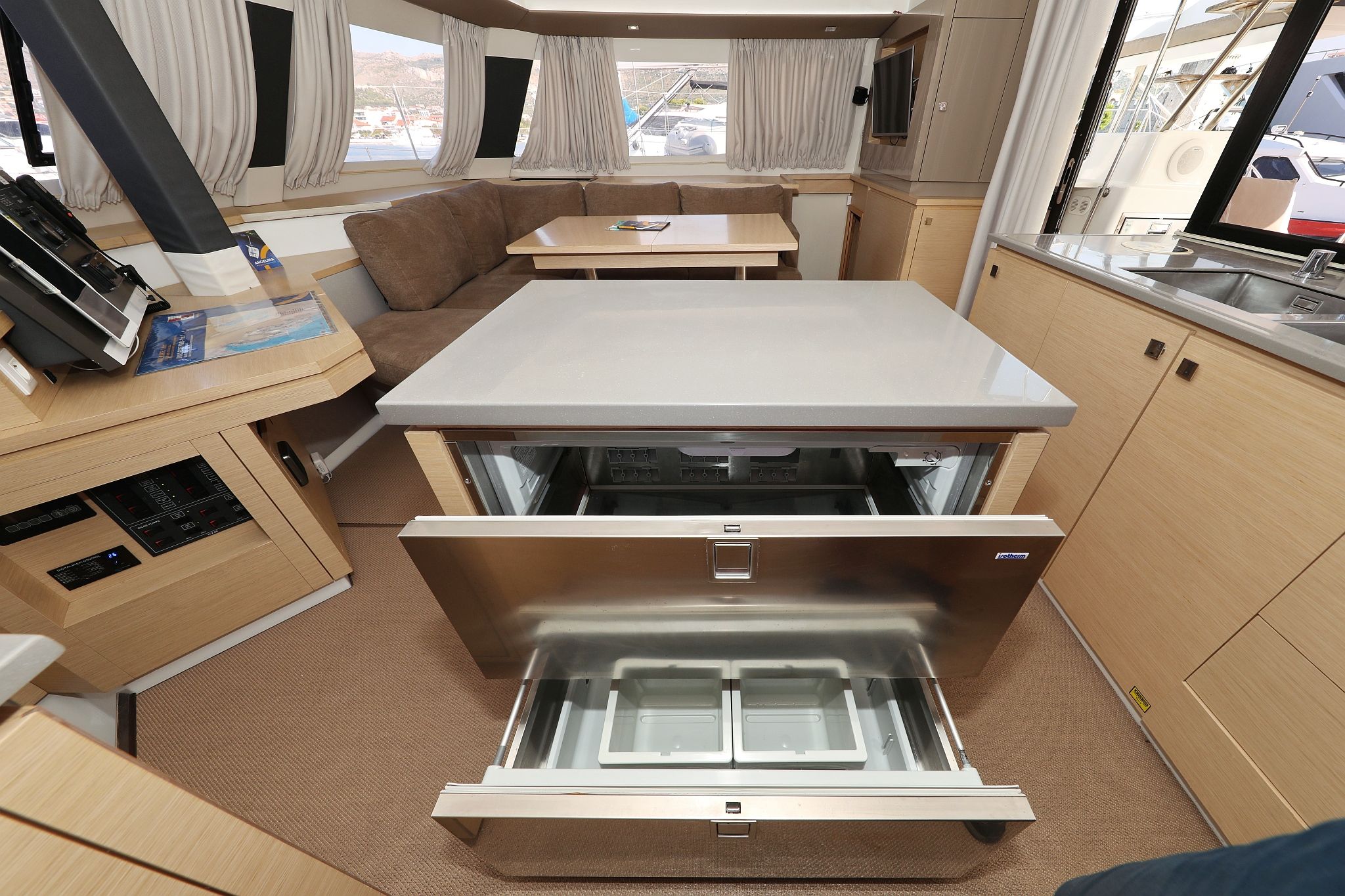 Ein kompaktes Wohnmobil-Interieur mit Küchenzeile, einer Essecke mit Tisch und Stühlen sowie einem Stauraumelement mit Schiebetür.