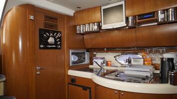 Une cuisine compacte avec des meubles en bois, un four à micro-ondes, un évier et un petit réfrigérateur.
