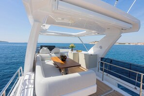Ein Yachthdeck mit Sitzgelegenheiten, einem Tisch und Blick aufs Meer.