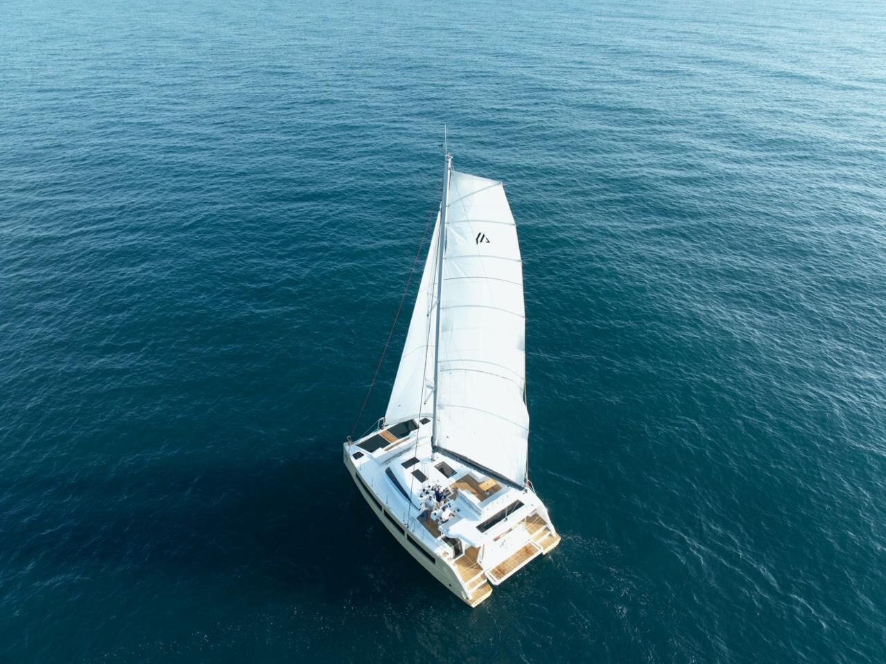 A sailboat with a cabin and deck seating, sailing on a calm sea.
