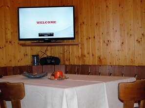 Ein Restaurantinneres mit einem Fernseher, der 'WELCOME' anzeigt, und einer Speisekarte.