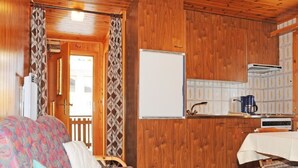 L’intérieur chaleureux d’un chalet, avec un revêtement mural en bois, un canapé, une table à manger et un coin cuisine.