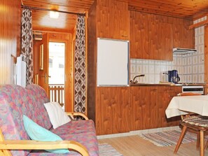 Ein gemütliches Blockhaus-Interieur mit Holzausstattung, einer Couch, einem Esstisch und einer Küchenzeile.