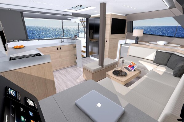 A modern yacht interior with a kitchen, dining area, and a lounge with a laptop and a drink tray. - Sun-Kissed Sailing Adventure in the Majestic Islas Baleares (Sant Antoni de Portmany)
