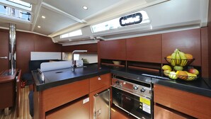 Una cocina pequeña con un lavabo, estufa y un bol de frutas en la encimera.