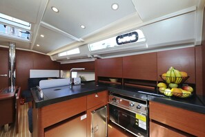 A compact kitchen with a sink, stove, and a fruit bowl on the counter. - Sun-Kissed Sailing Adventure in Northern Croatia (Novi Vinodolski)