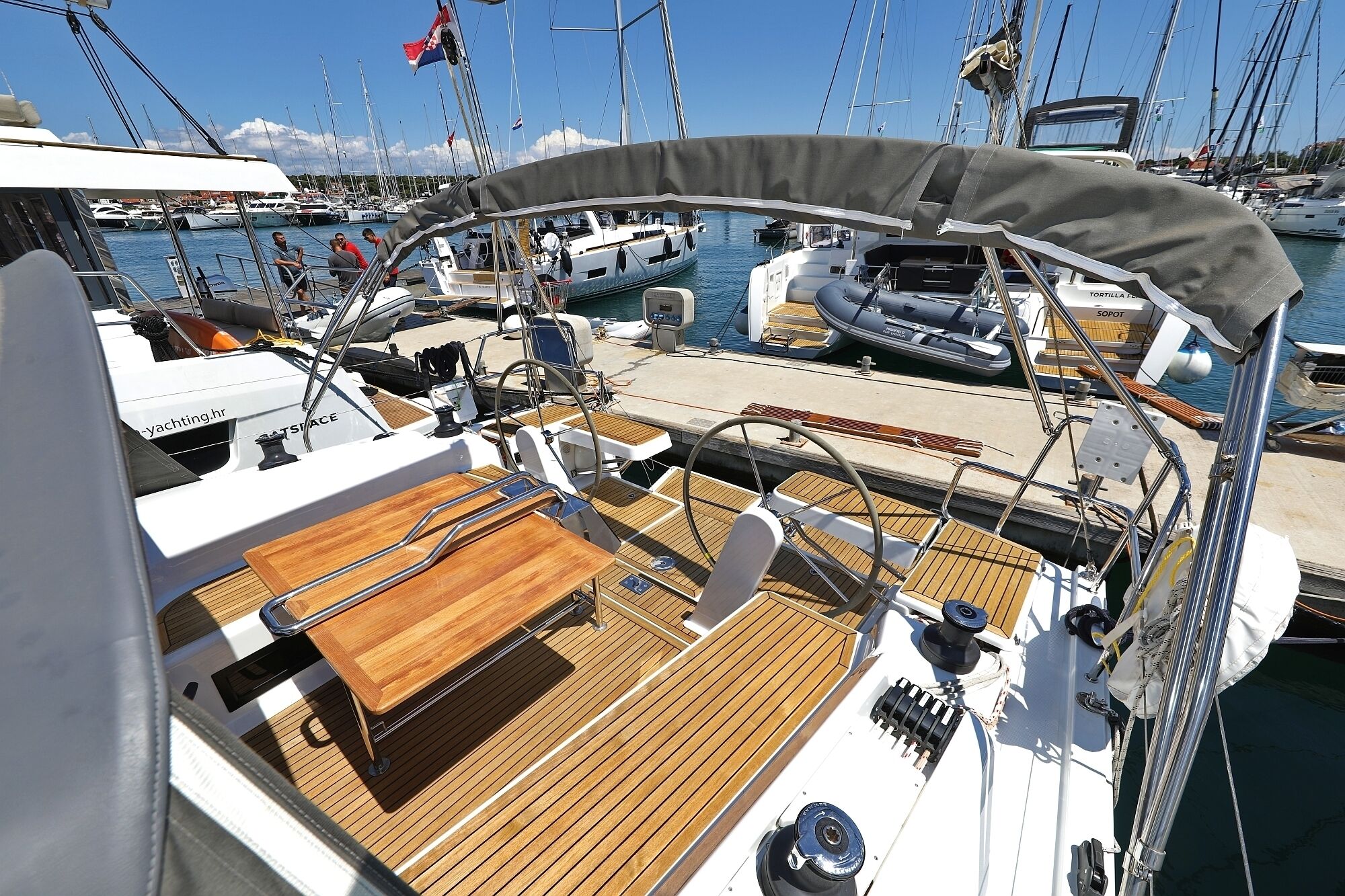 A marina with multiple boats docked, a wooden deck, and a covered area with a canopy.