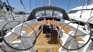Cubierta de barco con timón, una mesa de madera y varios mástiles.