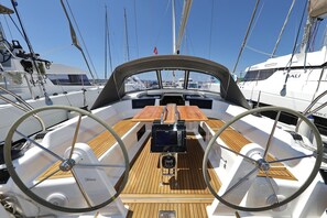 A boat's deck with a steering wheel, a wooden table, and multiple masts. - Sun-Kissed Sailing Adventure in Northern Croatia (Novi Vinodolski)