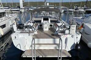 A marina with a boat featuring a steering wheel, a brand name 'BENETEAU' on the deck, and a logo 'S' on the helm. - Sun-Kissed Sailing Adventure in Northern Croatia (Punat)