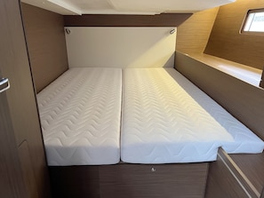 A compact bed with a herringbone mattress pattern, a small window, and a wooden headboard. - Sun-Kissed Sailing Adventure in Northern Croatia (Punat)