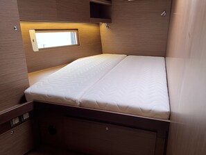 A compact bed with a headboard, a small window, and built-in storage drawers. - Sun-Kissed Sailing Adventure in Northern Croatia (Punat)