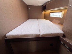 Een compacte camper met een enkel bed en een raam dat uitzicht biedt op de omgeving.