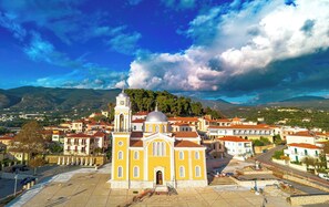 A yellow church with a bell tower, surrounded by residential buildings and a mountainous backdrop. - Sun-Kissed Sailing Adventure in Kalamata, Peloponeso (Kalamata)