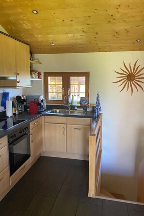 A kitchen with wooden cabinets, a stove, a sink, and a window. - Alphütte Bielerhüs Appartement/Fewo, Dusche, WC 3 Zimmerwohnung, 4-Betten by Interhome (Fiesch)