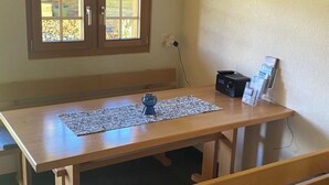 A wooden dining table with benches, a clock on the wall, and a window with a view of the outdoors. - Alphütte Bielerhüs Appartement/Fewo, Dusche, WC 3 Zimmerwohnung, 4-Betten by Interhome (Fiesch)