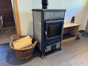 A wood-burning stove with a basket of firewood beside it. - Alphütte Bielerhüs Appartement/Fewo, Dusche, WC 3 Zimmerwohnung, 4-Betten by Interhome (Fiesch)