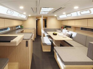 Ein modernes Wohnmobil-Interieur mit Küchenzeile, Sitzgelegenheiten und einem zentralen Tisch.
