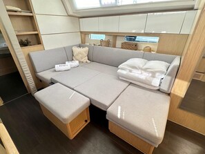 A compact living space with a sofa, pillows, and storage compartments. - Sun-Kissed Sailing Adventure in Islas Baleares, Mallorca (Palma)