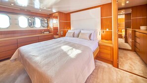 Ein geräumiges Schlafzimmer mit einem großen Bett, Holzwandverkleidung und Blick durch eine offene Tür.