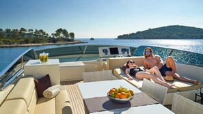 A yacht with a dining area, a control panel, and a view of the sea and a distant island. - Sun-Kissed Sailing Adventure in Split-Dalmacia, Croatia (Baška Voda)